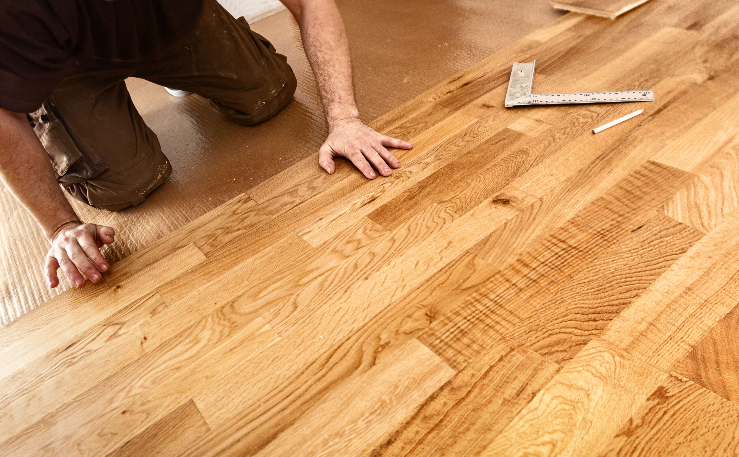 craftsman laying down wood flooring with precision